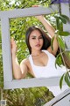 A woman in a white tank top leaning against a window.